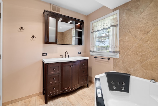 full bath featuring baseboards, a jetted tub, and vanity