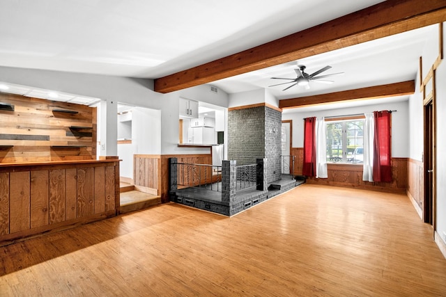 kitchen with wood finished floors, wainscoting, a ceiling fan, wooden walls, and beam ceiling