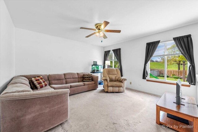 living area with ceiling fan, plenty of natural light, and carpet floors