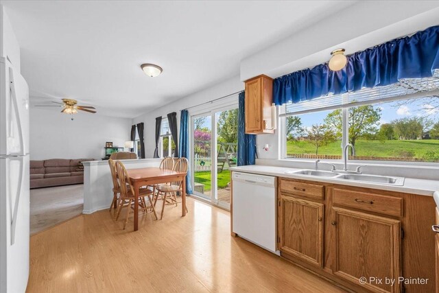 kitchen with white appliances, a sink, light wood-type flooring, and light countertops