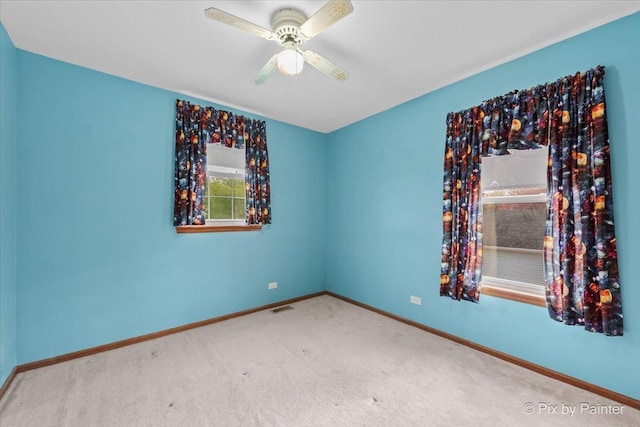 carpeted empty room with ceiling fan and baseboards