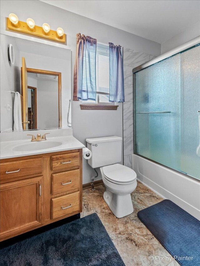 full bath featuring vanity, toilet, and shower / bath combination with glass door