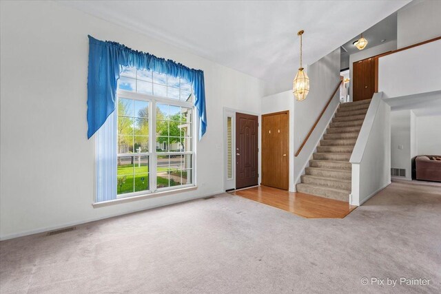 foyer entrance featuring carpet flooring and stairway