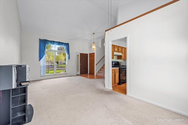 unfurnished living room with carpet, stairs, and baseboards