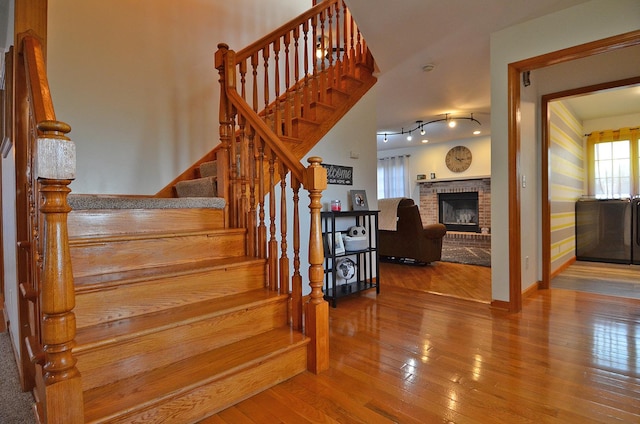 stairway featuring wood-type flooring and a brick fireplace