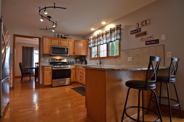 kitchen with appliances with stainless steel finishes, a sink, a peninsula, and healthy amount of natural light