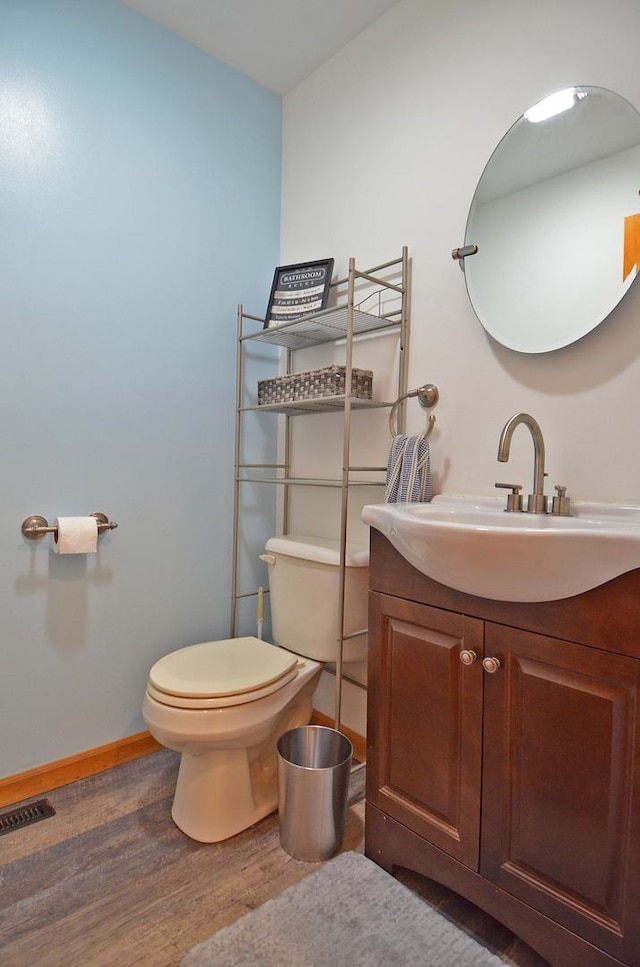 bathroom featuring wood finished floors, toilet, baseboards, and vanity