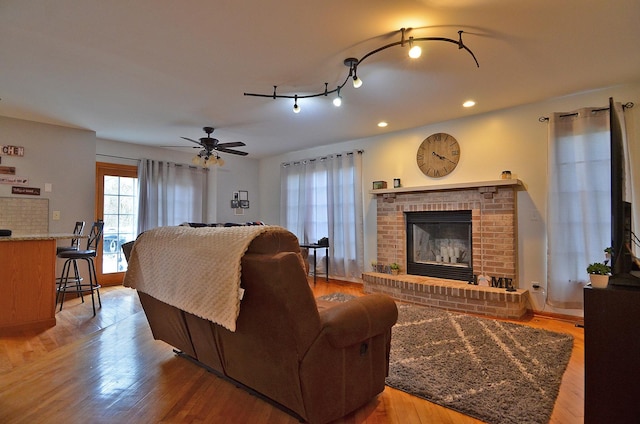 living room with a fireplace, wood finished floors, recessed lighting, and ceiling fan