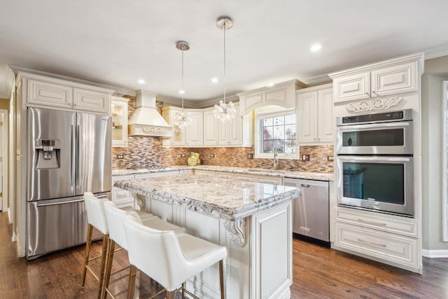kitchen with stainless steel appliances, premium range hood, a sink, backsplash, and recessed lighting