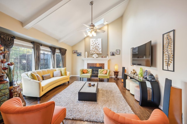 living area featuring ceiling fan, wood finished floors, a fireplace, beam ceiling, and high vaulted ceiling
