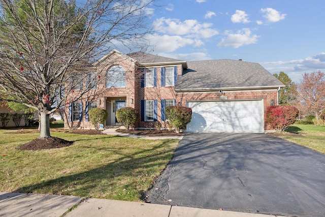colonial-style house featuring driveway, a garage, a front lawn, brick siding, and roof with shingles