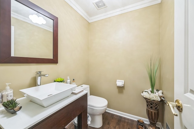 bathroom featuring toilet, crown molding, wood finished floors, baseboards, and vanity
