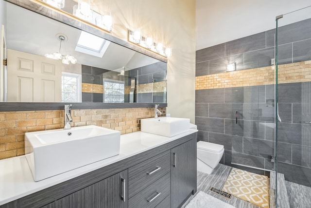 bathroom featuring a shower stall, double vanity, toilet, tile walls, and a skylight