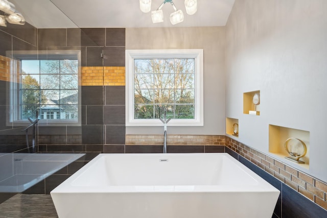 full bathroom with a soaking tub and healthy amount of natural light