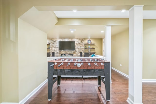 rec room featuring wood finished floors, baseboards, and ornate columns