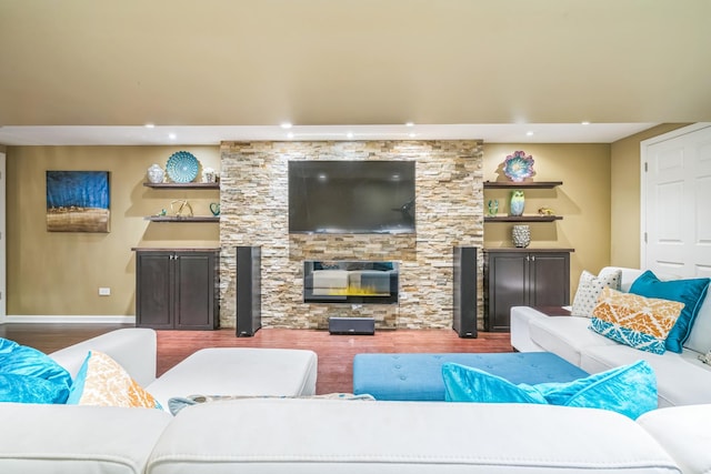 living area featuring wood finished floors, recessed lighting, baseboards, and a stone fireplace