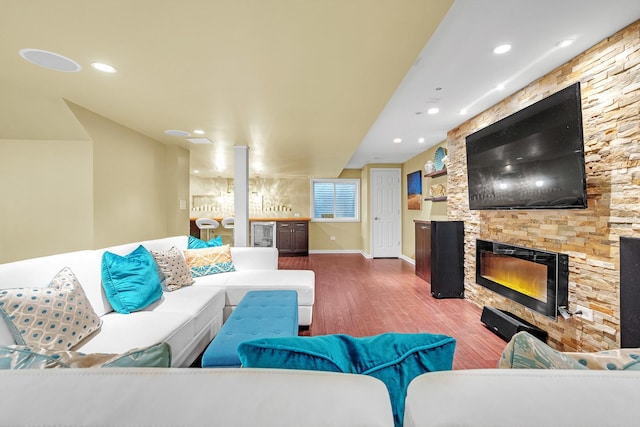 living area featuring wood finished floors, baseboards, a stone fireplace, beverage cooler, and recessed lighting