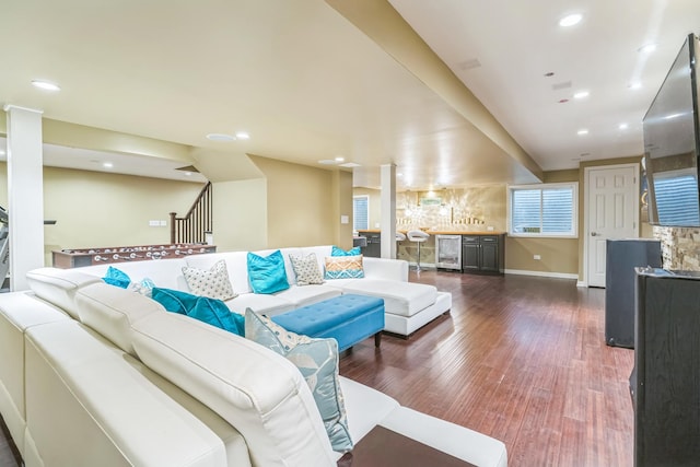 living room with wine cooler, bar area, dark wood-style floors, stairway, and baseboards