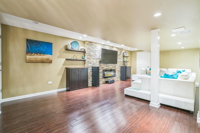 living room featuring wood finished floors, baseboards, a stone fireplace, and recessed lighting