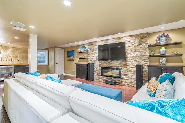 living room featuring wood finished floors, beverage cooler, recessed lighting, baseboards, and a stone fireplace