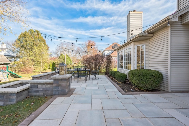 view of patio with outdoor dining area and a playground
