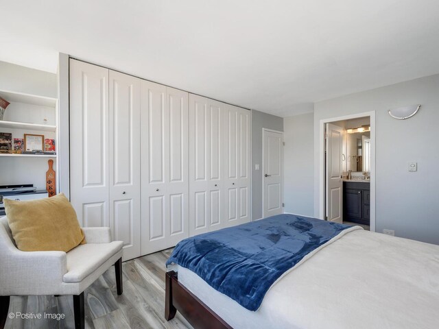 bedroom with light wood-style flooring, a closet, and ensuite bath