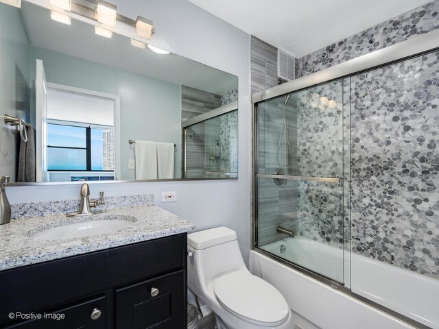 full bath with vanity, enclosed tub / shower combo, and toilet