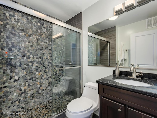 full bath featuring a stall shower, toilet, and vanity