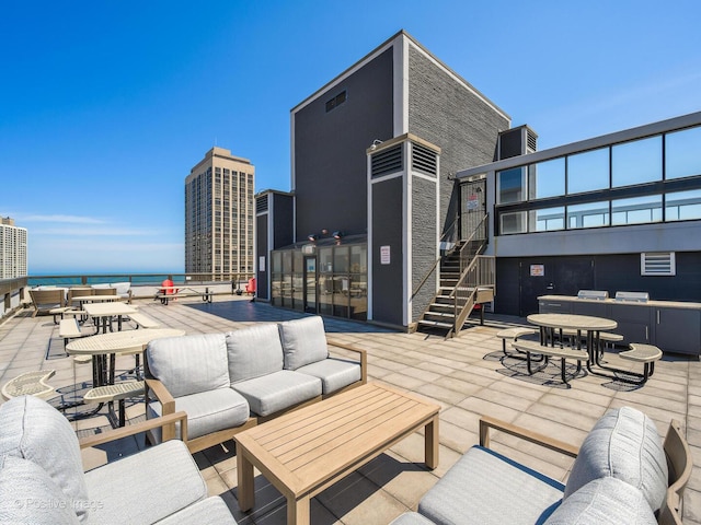 view of patio with an outdoor hangout area, stairway, and a water view