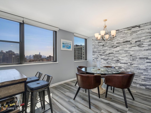dining space with a chandelier, wood finished floors, baseboards, and a skyline view