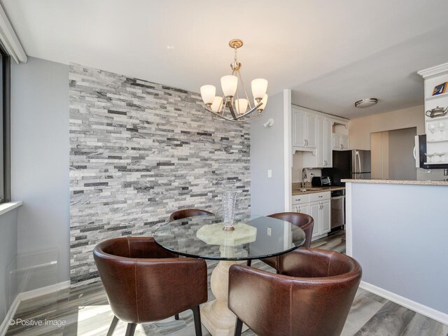 dining area with a chandelier, light wood-style flooring, and baseboards