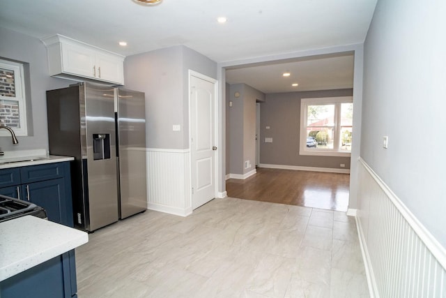 9539 S Forest Ave, Chicago, IL 60628 - kitchen with stainless steel refrigerator with ice dispenser, a sink, a wainscoted wall, white cabinetry, and blue cabinets