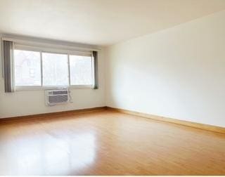 135 S Kenilworth Ave Unit 8, Oak Park, IL 60302 - empty room with wood finished floors, a wall mounted air conditioner, and baseboards