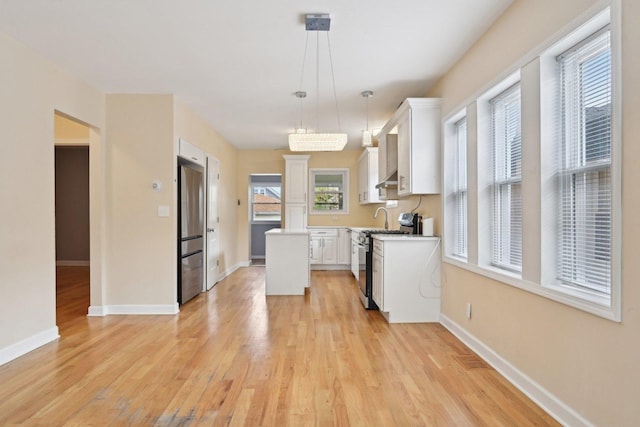 5814 W Roscoe St, Chicago, IL 60634 - kitchen featuring stainless steel appliances, light wood finished floors, white cabinetry, and a center island