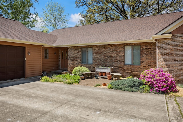 3262 Greenwood Dr, Dewey, IL 61840 - property entrance with brick siding, an attached garage, roof with shingles, and driveway