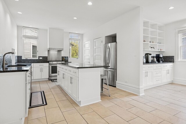 kitchen with stainless steel appliances, a sink, white cabinetry, light tile patterned floors, and a kitchen island