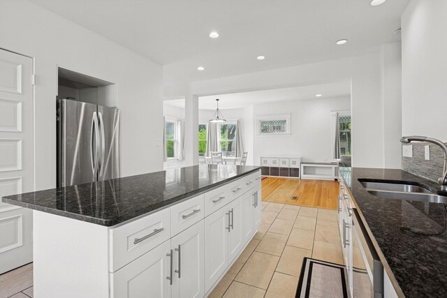 kitchen featuring freestanding refrigerator, a sink, dishwasher, dark stone counters, and recessed lighting