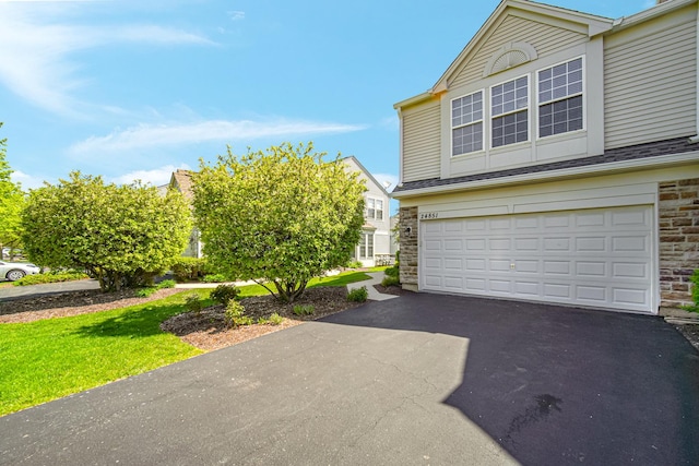 view of side of home featuring an attached garage, asphalt driveway, and stone siding