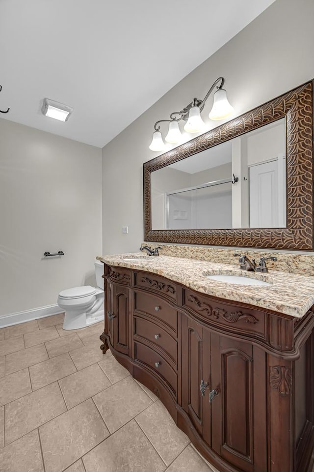 full bath featuring toilet, tile patterned floors, double vanity, a shower with shower door, and baseboards