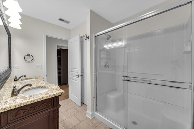 full bath with a shower stall, tile patterned flooring, and double vanity