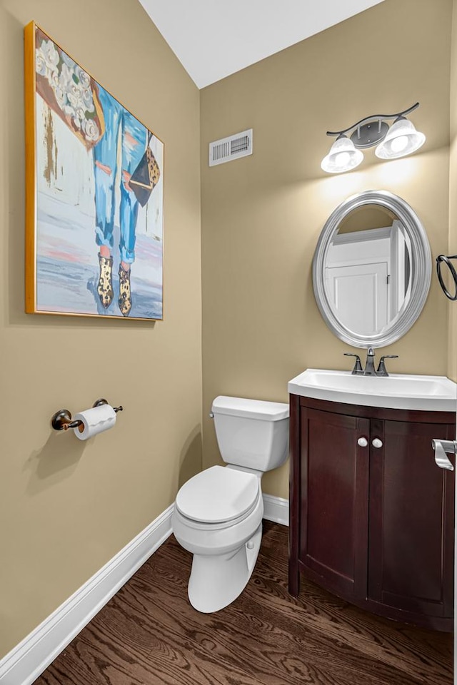 bathroom with baseboards, wood finished floors, toilet, and vanity