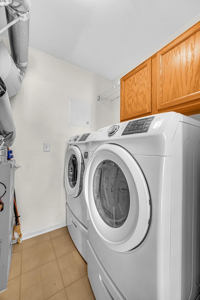 washroom featuring separate washer and dryer, cabinet space, and baseboards
