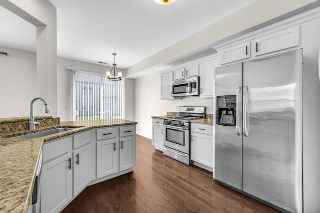kitchen with stainless steel appliances, a sink, dark wood finished floors, light stone counters, and a chandelier