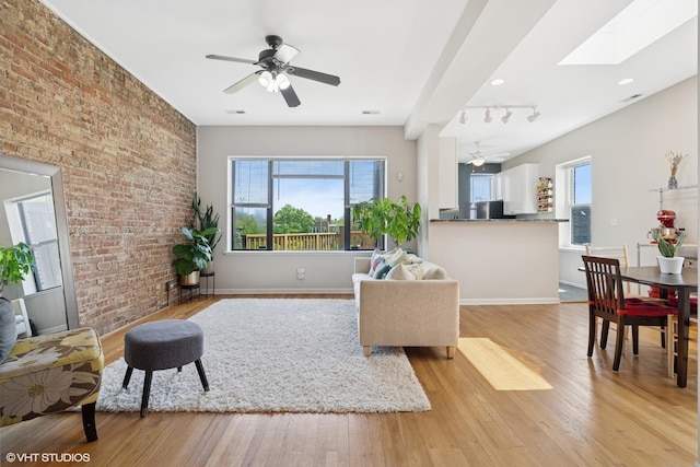 4817 N Fairfield Ave Unit 3, Chicago, IL 60625 - living room with light wood-type flooring, ceiling fan, baseboards, brick wall, and a skylight