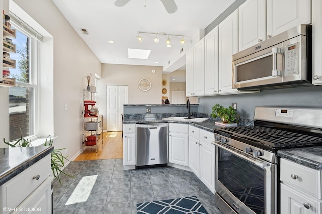 4817 N Fairfield Ave Unit 3, Chicago, IL 60625 - kitchen with appliances with stainless steel finishes, a skylight, a sink, a peninsula, and white cabinets