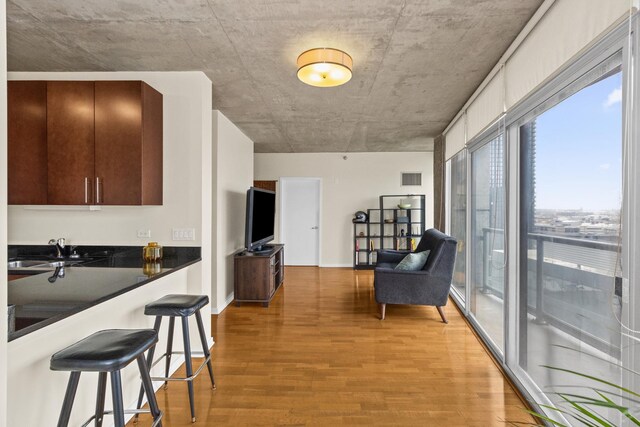 kitchen with a sink, dark countertops, a breakfast bar, light wood-type flooring, and open floor plan
