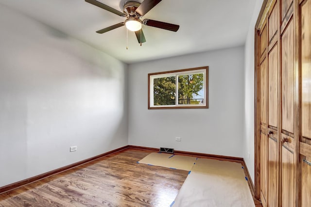empty room featuring a ceiling fan, wood finished floors, and baseboards