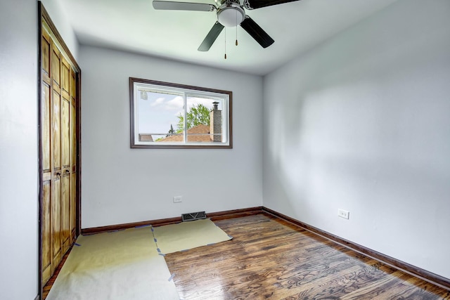 unfurnished bedroom with a closet, baseboards, wood finished floors, and a ceiling fan