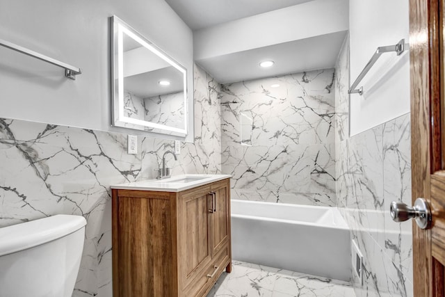 bathroom featuring tile walls, toilet, vanity, marble finish flooring, and bathing tub / shower combination