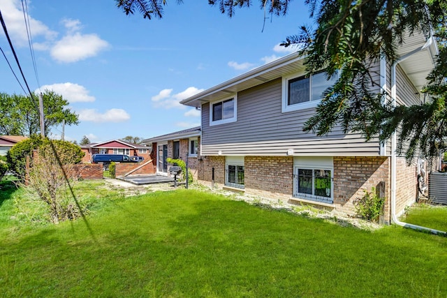 back of house with a lawn, brick siding, and cooling unit